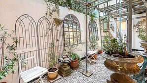 A covered garden area with potted plants, a bench, and a decorative stone fountain. - Richmond Hill Top Apartment (London)