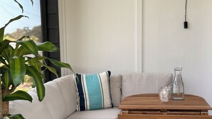 Un rincón acogedor con un banco acolchado, una mesa de madera y una planta en maceta.