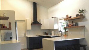 Una cocina moderna con una isla central, armarios oscuros y una campana extractora negra.