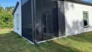Una casa moderna con un amplio ventanal corredero que da a un espacio exterior cubierto.