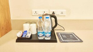 Minibar im Hotelzimmer mit Wasserflaschen, einer Kaffeemaschine und einer Auswahl an Snacks sowie einer Speisekarte.