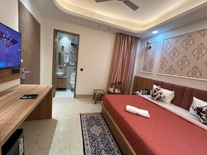 Een hotelkamer met een bed, bureau, televisie, badkamer en douche.