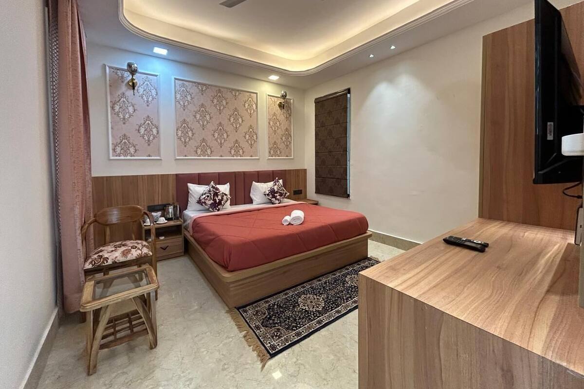 Une chambre d’hôtel moderne équipée d’un lit, d’un bureau en bois, d’une chaise, d’une télévision et d’un ventilateur de plafond.
