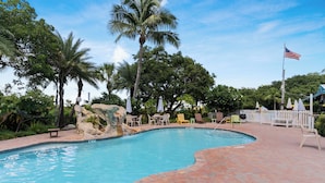 A swimming pool with a 5 ft depth marker, surrounded by palm trees and a white picket fence. - The Ocean View Inn & Pub (Islamorada)