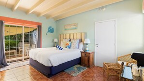 A bedroom with a bed, a nightstand, a chair, and a door. - The Ocean View Inn & Pub (Islamorada)