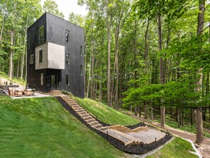 Un edifici modern de dues plantes amb teulada plana, envoltat per un bosc.