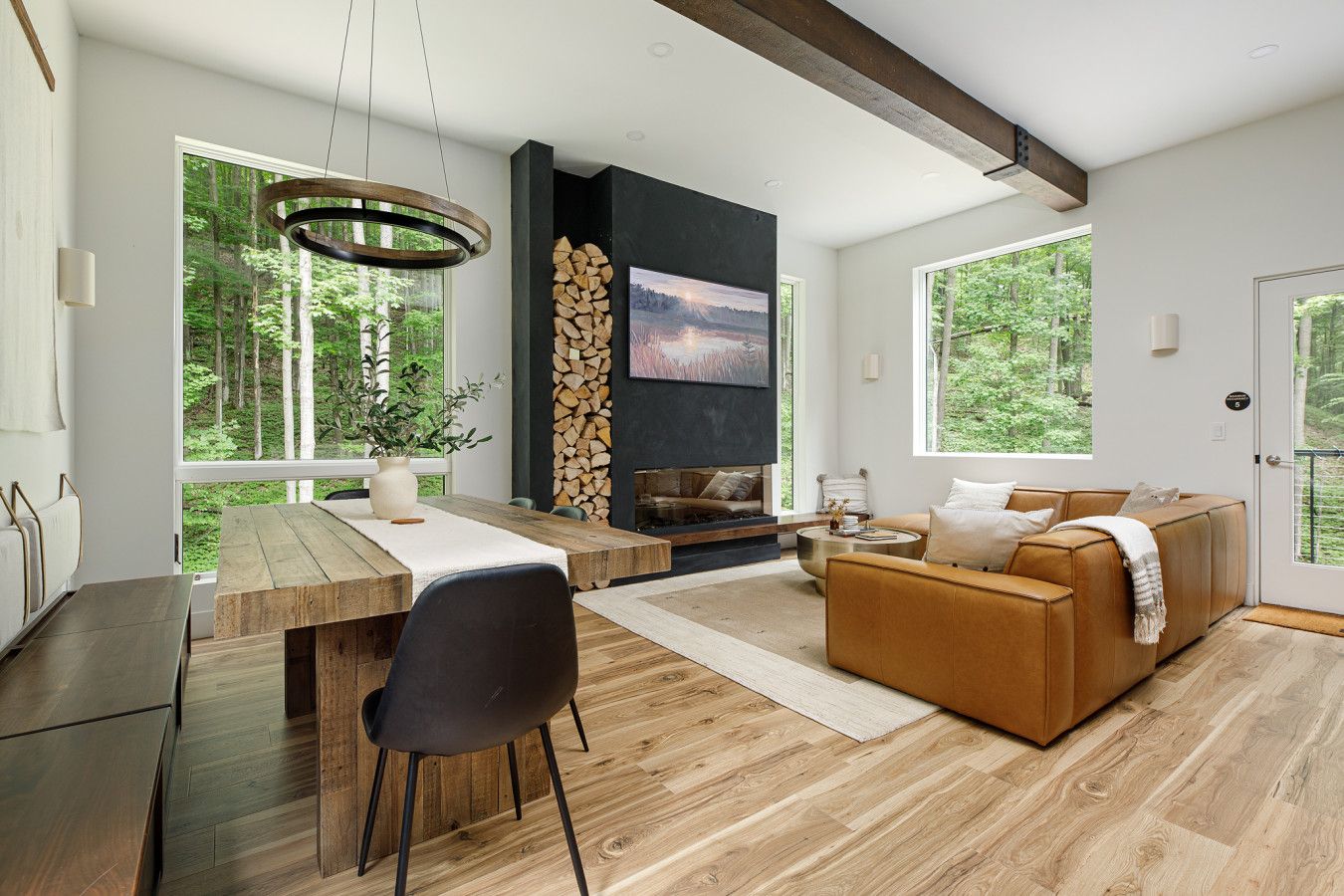 A modern living room with a wooden dining table, a sofa, and a fireplace.