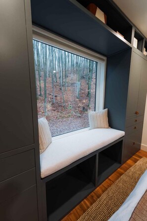 Habitació amb una cadira integrada al costat d'una finestra amb vista a un bosc.