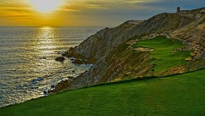 A coastal landscape with a golf course, a rocky cliff, and a building on top. - 3BDOceanview Villa at MontecristoEstates (Cabo San Lucas)