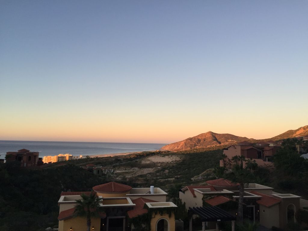 Zona residencial costera con casas de tejas rojas y una montaña al fondo.