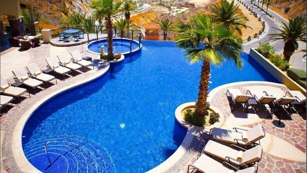A pool with lounge chairs and palm trees, surrounded by a mountainous landscape. - 3BDOceanview Villa at MontecristoEstates (Cabo San Lucas)