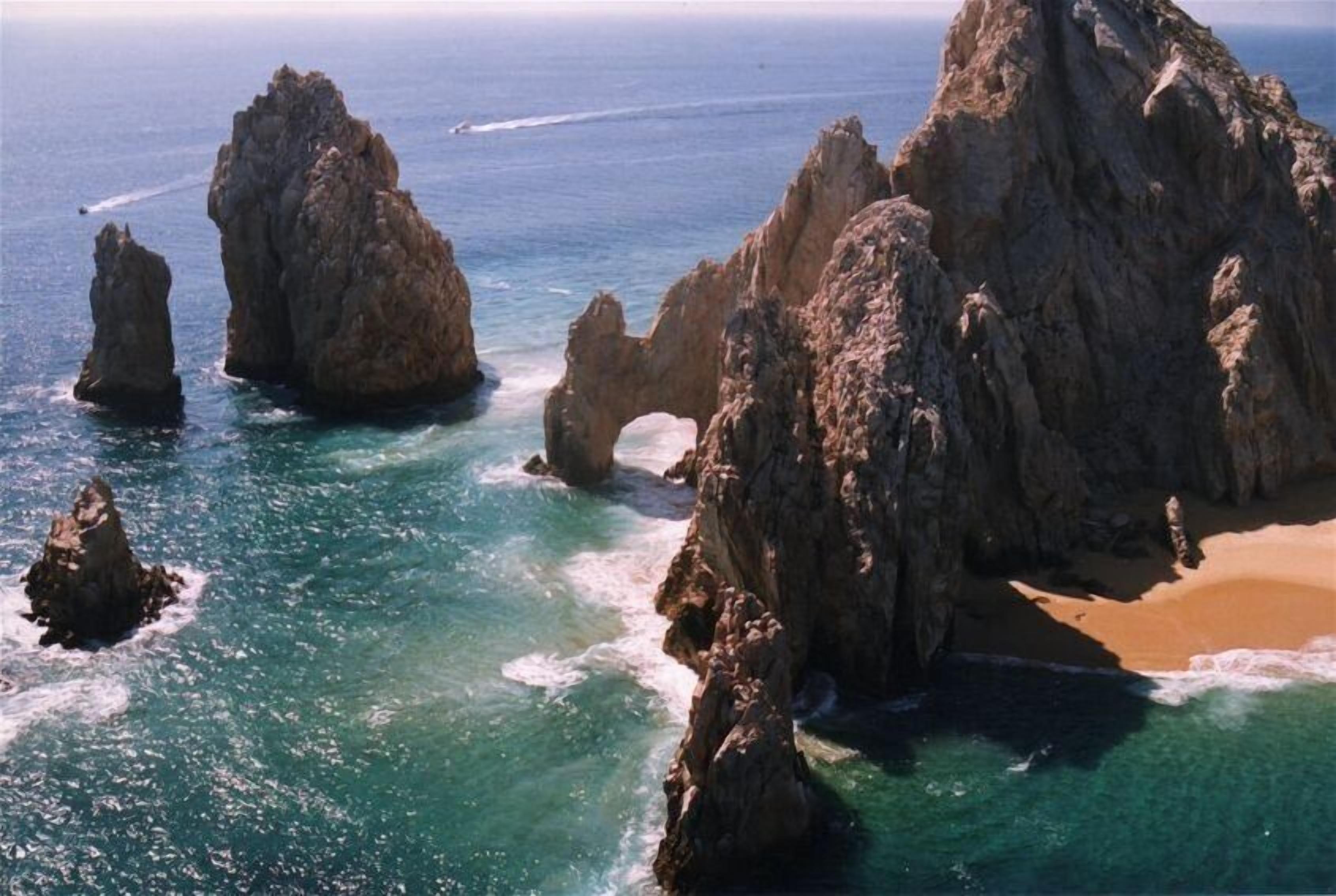 Un paysage côtier caractérisé par d’imposantes formations rocheuses et une plage de sable.