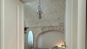 A bedroom with a bed, a white door, a textured wall, and a hanging light fixture. - Montesanto 60 Suite in the historic center of Alberobello (Alberobello)