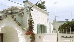 A white building with a stone archway, a metal gate with a sign, and a satellite dish. - Montesanto 60 Suite in the historic center of Alberobello (Alberobello)