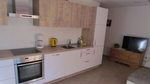 A modern kitchen with stainless steel appliances, wooden cabinets, and a built-in oven.