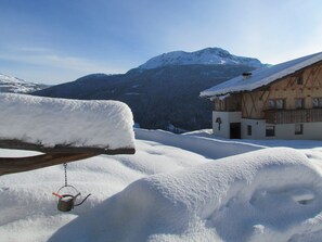 Ett snötäckt berglandskap med en träbyggnad som har en balkong och ett trästaket.