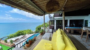 Un área junto a la piscina con un sofá amarillo, una piscina y vistas al océano.