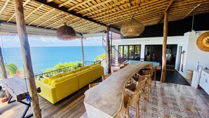 Una terraza de madera con un sofá amarillo, una mesa de billar y vista al océano.