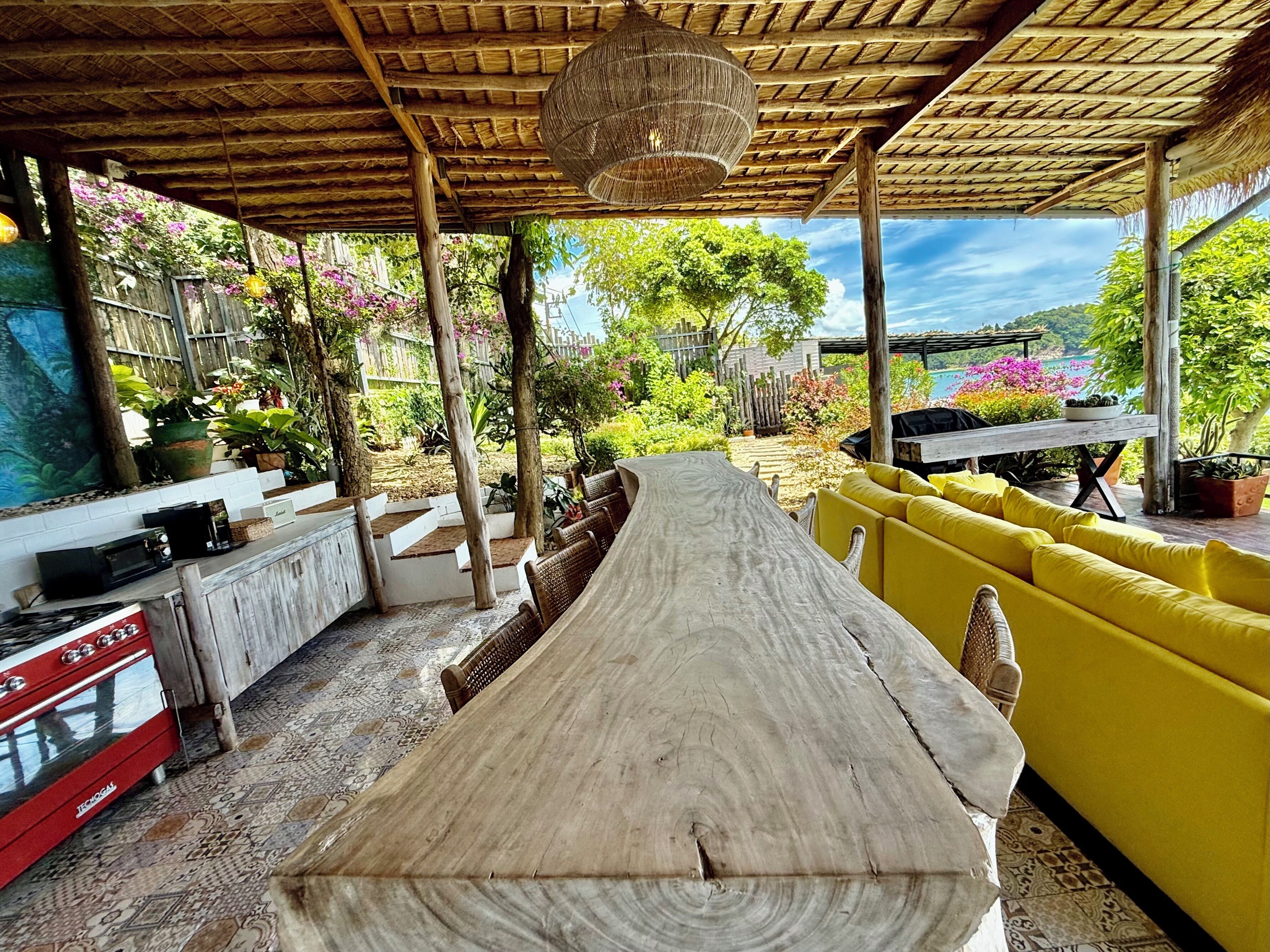 A wooden dining table with chairs, a yellow sofa, and a grill.
