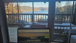 A laptop on a wooden desk with a view of a marina through a window.