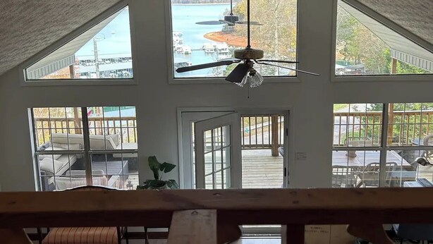 A spacious room with a high ceiling, large windows, and a view of a lake.
