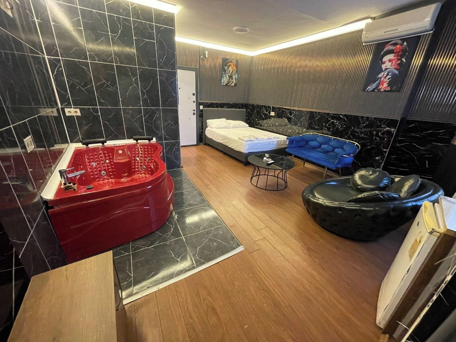Un baño moderno con un jacuzzi rojo, una cama, un sofá azul y un otomano negro.