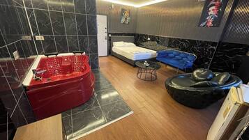 Un baño moderno con un jacuzzi rojo, una cama, un sofá azul y un otomano negro.