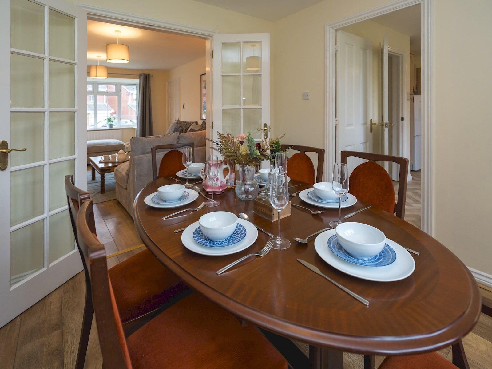 A dining room with a wooden table set for four, surrounded by chairs.