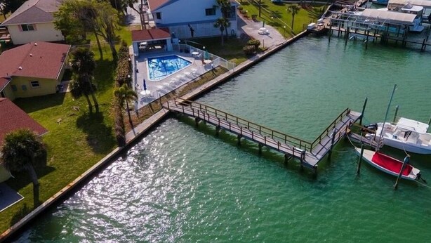 A waterfront property with a swimming pool, dock, and boats. - 2BR at Sandpiper Cove – Pool, Bay, Beachwalk (Englewood)