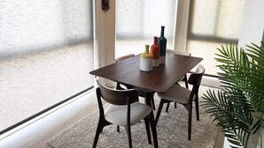 A dining area with a wooden table and chairs, a small plant, and a window with blinds. - 2BR at Sandpiper Cove – Pool, Bay, Beachwalk (Englewood)