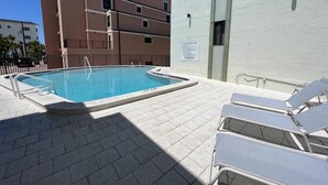 A swimming pool with lounge chairs, a no driving sign, and a building in the background. - La Coquina 2BR – Beachfront w/ Pool & Views (Englewood)