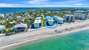 An aerial view of a coastal resort with beachfront properties, including a large building highlighted in the center. - La Coquina 2BR – Beachfront w/ Pool & Views (Englewood)