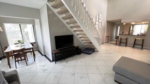 Un vaste espace de vie comprenant un escalier, une table à manger et un canapé.
