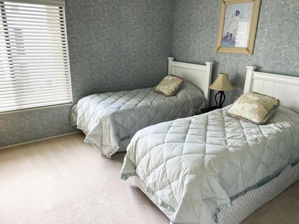A bedroom with two beds, each with a pillow and a lamp.