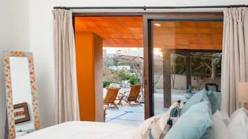 Een slaapkamer met een bed en een schuifdeur die leidt naar een terras met stoelen en een tafel.