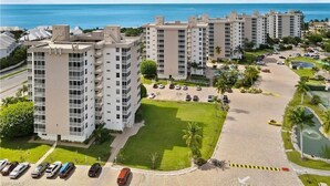 Een hoog appartementencomplex met meerdere balkons, een parkeerplaats en uitzicht op de oceaan.