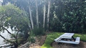 A picnic table by a lake with a grassy area and trees. - Lemon Bayview Villa - Heated Pool - Tennis - Dock (Englewood)