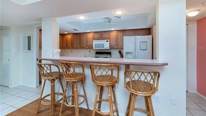 A modern kitchen with a central island, wooden cabinets, and a ceiling fan.