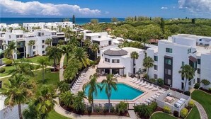 A resort with modern buildings, a central pool, and a view of the ocean.