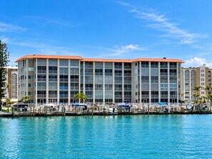 Un hôtel à plusieurs étages offrant une vue sur le front de mer, doté de balcons et d’un port de plaisance avec des bateaux.