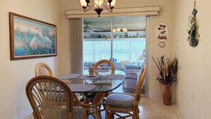A dining area with wicker chairs, a glass table, and a chandelier. - 2BR on Oyster Creek – Boat Dock & Beach (Englewood)