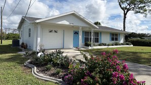 A single-story house with a white exterior and blue trim, a front porch, and a driveway leading to a garage. - 2BR on Oyster Creek – Boat Dock & Beach (Englewood)