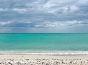 Una playa con agua turquesa cristalina y un cielo nublado.