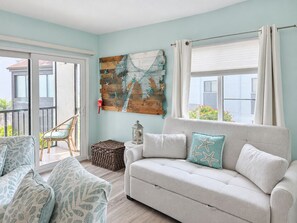 A living room with a sofa, a wicker chair, and a decorative wall piece.