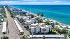 An aerial view of a coastal hotel with multiple white buildings, a road, and a beach.