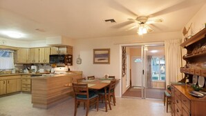 Una cocina amplia con armarios de madera, un comedor con mesa y sillas, y un ventilador de techo.