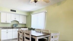 A dining area with a table and chairs, a ceiling fan, and white cabinets. - Bayside 2BR Condo at Tamarind - Private Sun Deck (Englewood)
