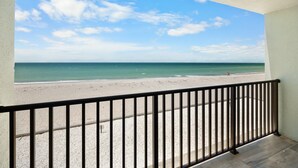 A balcony with a view of a beach and ocean.
