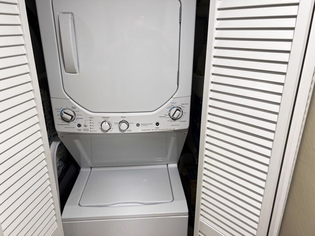 A compact, white washing machine with a control panel featuring multiple settings and a small step for loading.