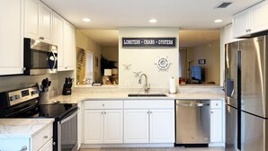 Una cocina moderna con armarios blancos, electrodomésticos de acero inoxidable y un cartel en la pared.